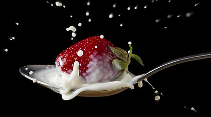 Image showing red, ripe strawberry falling in spoon with milk