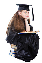 Image showing girl in black academic cap and gown reading big blue book