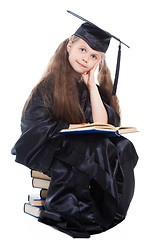 Image showing girl in black academic cap and gown reading big blue book