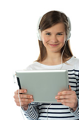 Image showing Beautiful girl listening to music via wireless tablet