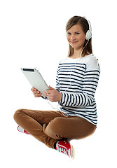 Image showing Seated girl enjoying music on portable device