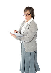 Image showing Senior woman writing in spiral notebook