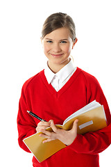 Image showing Happy young girl writing on notebook