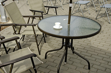 Image showing Empty coffee cup on table and chairs on pavement 