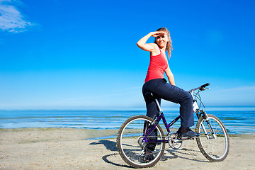 Image showing beautiful woman with bicycle at the sea