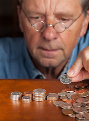 Image showing Senior man counting cash into piles