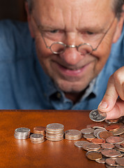 Image showing Senior man counting cash into piles