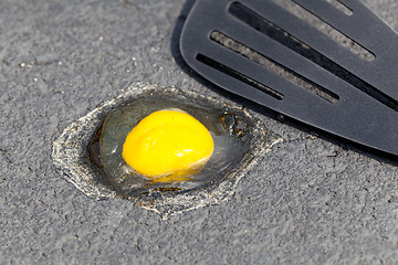 Image showing Egg on hot road surface beginning to fry