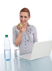 Image showing young business woman on computer with snack isolated 