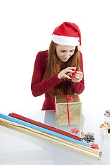 Image showing young woman is packing  present for christmas isolated