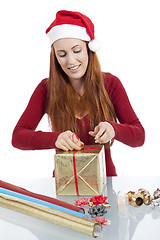 Image showing young woman is packing  present for christmas isolated