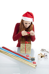 Image showing young woman is packing  present for christmas isolated