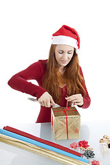 Image showing young woman is packing  present for christmas isolated