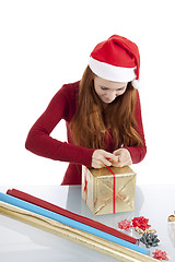 Image showing young woman is packing  present for christmas isolated