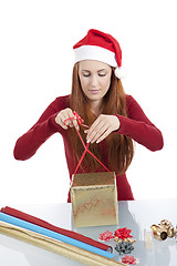 Image showing young woman is packing  present for christmas isolated