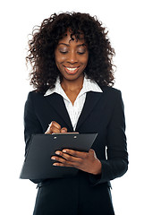 Image showing African female executive writing on notepad