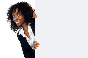 Image showing Woman peeping from behind white placard