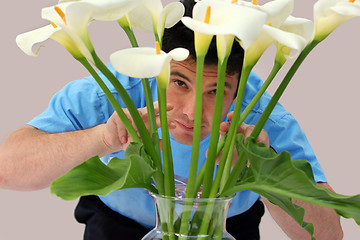 Image showing Man peeking through flowers