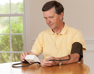 Image showing Senior man taking blood pressure at home