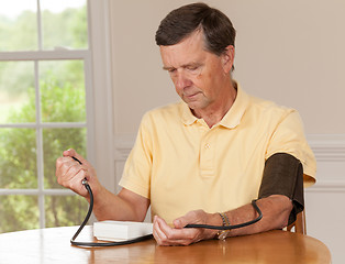 Image showing Senior man taking blood pressure at home