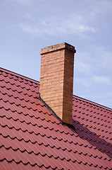 Image showing Brown tiled roof yellow brick chimney on sky 