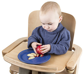 Image showing young child eating peaches in high chair