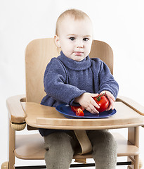 Image showing young child eating in high chair