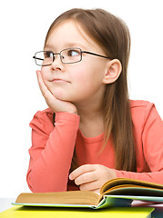 Image showing Cute little girl is dreaming while reading book