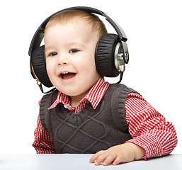 Image showing Cute little boy enjoying music using headphones