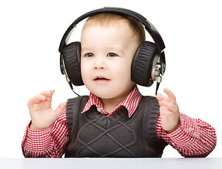Image showing Cute little boy enjoying music using headphones