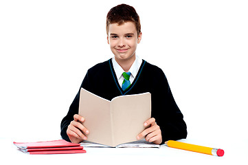 Image showing Cute school kid holding notebook and reading