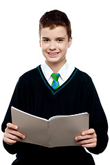 Image showing Charming schoolboy holding workbook