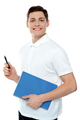 Image showing Smiling young man with notepad and pen