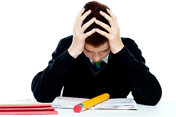 Image showing Confused student holding his head in classroom