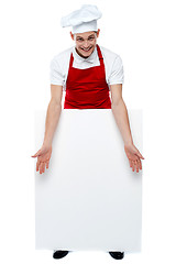 Image showing Handsome young cook showing blank billboard