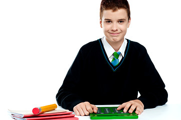 Image showing Smiling young boy using calculator