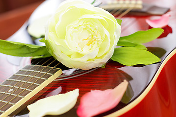 Image showing Romantic love concept - white rose on red guitar, background