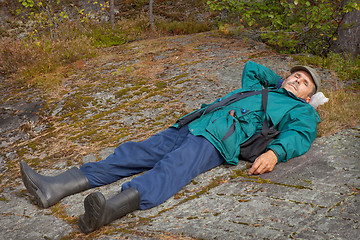 Image showing Elderly tourist resting on the rock