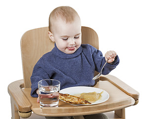 Image showing young child eating in high chair