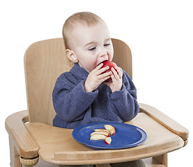 Image showing young child eating peaches in high chair