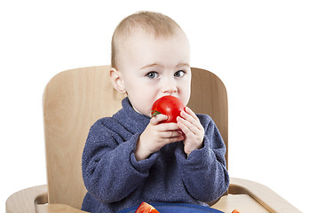 Image showing young child eating in high chair