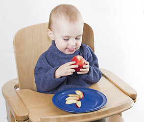 Image showing young child eating peaches in high chair