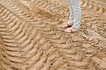 Image showing woman legs stand on quarry sand truck tracks 