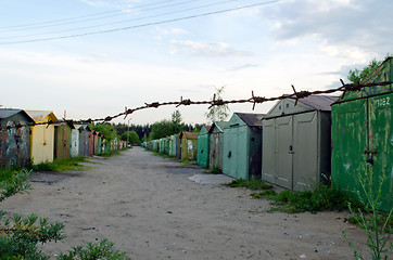 Image showing Rusty metal car park garages fence in barbed wire 