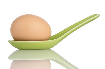 Image showing Brown egg in a green ceramic spoon