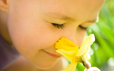 Image showing Portrait of a cute little girl smelling flowers