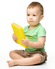 Image showing Cute little boy reads a book