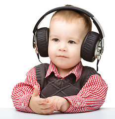 Image showing Cute little boy enjoying music using headphones