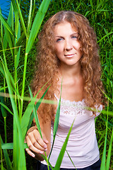 Image showing beautiful girl in pink among high green grass of summer meadow
