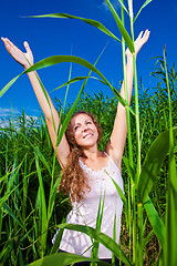 Image showing beautiful girl in pink among high green grass of summer meadow